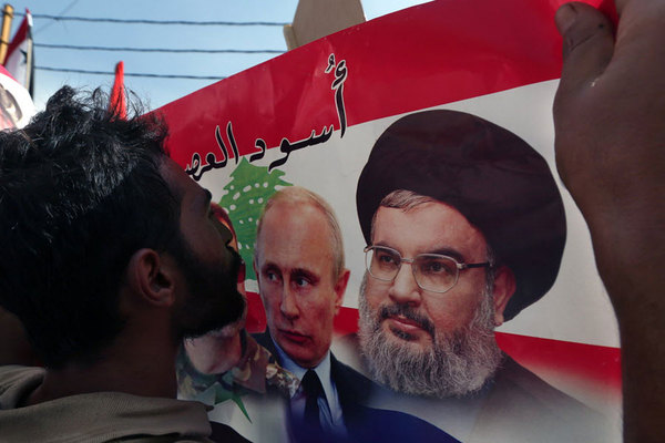 A Syrian who lives in Lebanon kisses a poster with photos of Russian President Vladimir Putin and Hezbollah leader Hassan Nasrallah during a rally in front of the Russian embassy in Beirut 