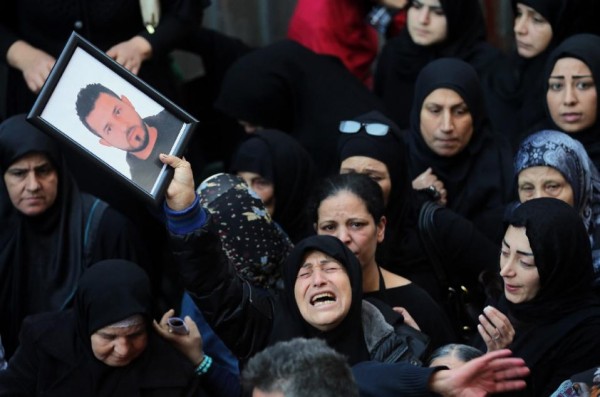 A relative of Samer Huhu, killed in a twin bombing attack that rocked a busy shopping street in the area of Burj al-Barajneh, waves his portrait as she mourns during his funeral in the southern suburb of the capital Beirut on November 13, 2015 (AFP Photo/Joseph Eid)