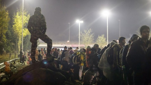  Refugees and migrants wait under the surveillance of soldiers to cross the Slovenian-Austrian border on November 6, 2015