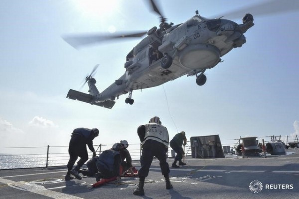 U.S. Navy Sailors participate in a medical training exercise on the deck of the Arleigh Burke-class guided missile destroyer USS Lassen with an MH-60R Seahawk helicopter, in the South China Sea