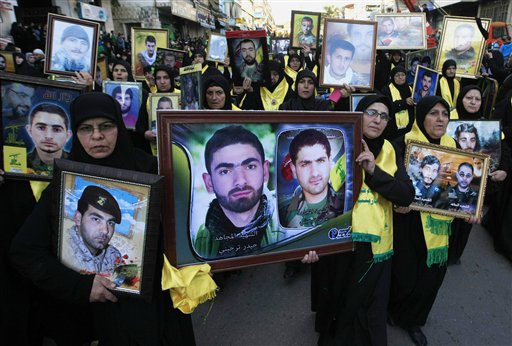In this Friday, Nov. 7, 2014 file photo, Lebanese Hezbollah supporters carry pictures of Hezbollah fighters who were killed in battle in Syria and against Israel, during a rally to mark the 13th day of Ashoura, in the southern market town of Nabatiyeh, Lebanon. At tightly guarded facilities in south Lebanon, men as young as 17 undergo intensive training on how to use automatic rifles and heavy machine guns before being shipped off to Syria to fight alongside President Bashar Assad's forces. The training is part of a massive Hezbollah recruitment effort to make up for its human losses in Syria's war, now approaching the death toll incurred by the group during 18 years of fighting Israeli occupation.(AP Photo/Mohammed Zaatari, File)