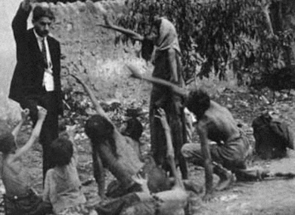 Turkish official teasing starved Armenian children by showing bread during the Armenian Genocide, 1915