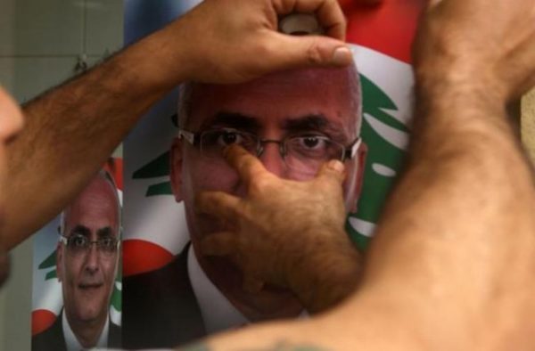 A Lebanese man puts up a poster of a candidate for the upcoming elections. (AFP/File