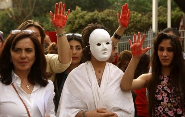 Lebanese women flash the palm of their hands colored in red as they demonstrate against prostitution, sex slavery and violence against women in front of the Justice Palace in the capital Beirut on April 8, 2016. / AFP PHOTO / PATRICK BAZ