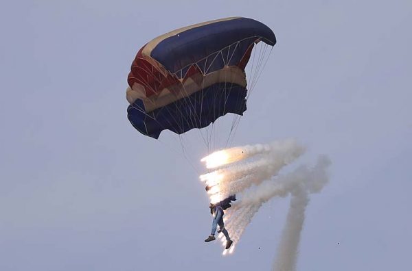 Pyrotechnics explode as a military parachutist descends upon Kalma Airport on Sunday, Sept. 25, 2016, in Wonsan, North Korea. Thousands of Koreans and hundreds of foreign tourists and journalists invited to Wonsan, a port city, for the Wonsan International Friendship Air Festival, were given a glimpse of North Korea's own Air Force fighters, remote-controlled scale mock-up planes including an F-16 fighter jet, and demonstrations of military parachuting, with the first two skydivers descending with huge North Korean and ruling party flags. (AP Photo/Wong Maye-E)