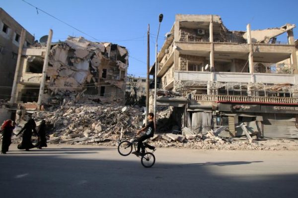 A boy plays with a bicycle past damaged buildings in the rebel held Seif al-Dawla neighbourhood of Aleppo, Syria October 6, 2016. REUTERS/Abdalrhman Ismail