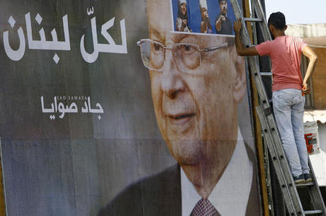 A worker hangs a billboard showing Christian leader Michel Aoun with Arabic that reads "For all Lebanon," in the southern port city of Sidon, Lebanon, Sunday, Oct. 30, 2016. Aoun, an 81-year-old veteran Christian politician, was elected by Parliament on Monday as part of a political deal with his rivals(AP Photo/Mohammed Zaatari)
