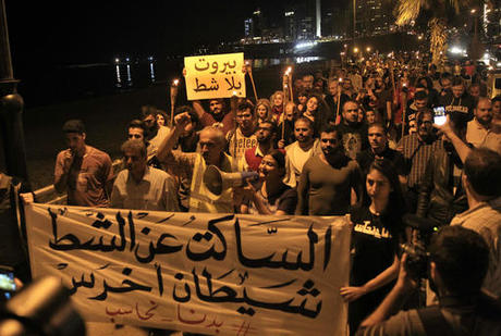 In this Tuesday, Nov. 15, 2016 photo, activists hold torches at a demonstration against the Eden Rock Resort development on Beirut's Ramlet al-Baida shore, Lebanon. Ramlet al-Baida is an outlet for locals and foreigners who can't pay for Lebanon's expensive private beaches. But a new luxury development project is set to turn its southern corner into another exclusive alcove. The banners in Arabic read, "Beirut without a shore," top, and "Whoever is silent about the beach is a mute devil," bottom. (AP Photo/Bilal Hussein)