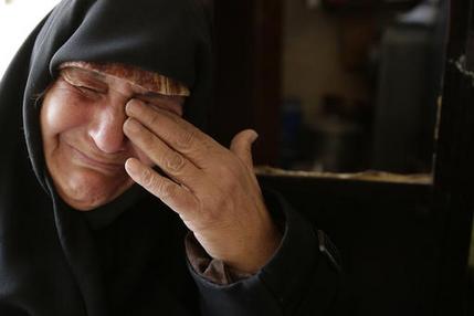 In this Sunday, Dec. 4, 2016 photo, Amina Hamawy cries after she returned to her looted home in the Hanano district of eastern Aleppo, Syria. It's a painful homecoming shared by hundreds of Syrians who are returning to areas devastated by years of war and then retaken from the city's embattled rebels in a recent government offensive. More than 30,000 people have fled Aleppo since the latest government offensive began last month, joining the more than 10 million Syrians -- nearly half the population -- who have fled their homes since the conflict began. (AP Photo/Hassan Ammar)
