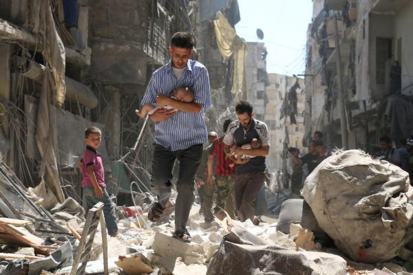 Syrian men carrying babies make their way through the rubble of destroyed buildings following a reported air strike on the rebel-held Salihin neighborhood of the northern city of Aleppo, on September 11. AMEER ALHALBI/AFP/GETTY
