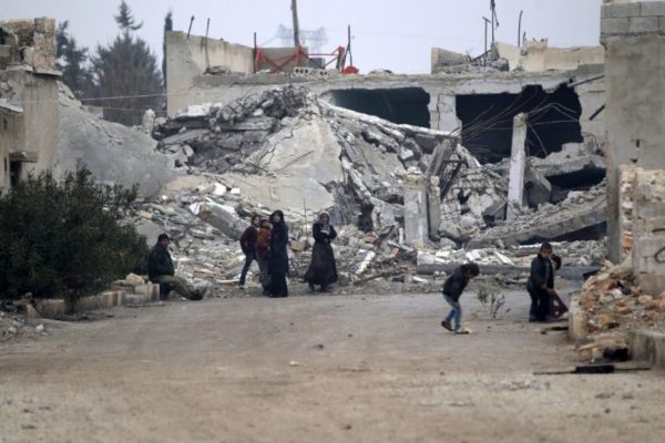 People stand near near rubble of damaged buildings in al-Rai town, northern Aleppo