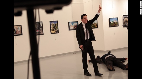 A body lies on the ground as a man with a pistol gestures at the scene of a shooting in Ankara, Turkey, on December 19.