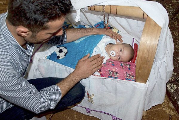 Hassan Jamil, a Kurdish peshmerga fighter, is seen with his infant son, Trump Jamil Hassan — a.k.a. “Little Trump” — in his living room in Chrra, Iraq. (Washington Post/Peter Holley)