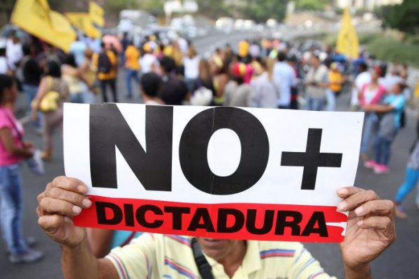 Opposition supporters holding a placard that reads, "No more dictatorship" shout slogans as they block a highway during a protest against Venezuelan President Nicolas Maduro's government in Caracas, Venezuela March 31, 2017. REUTERS/Carlos Garcia Rawlins