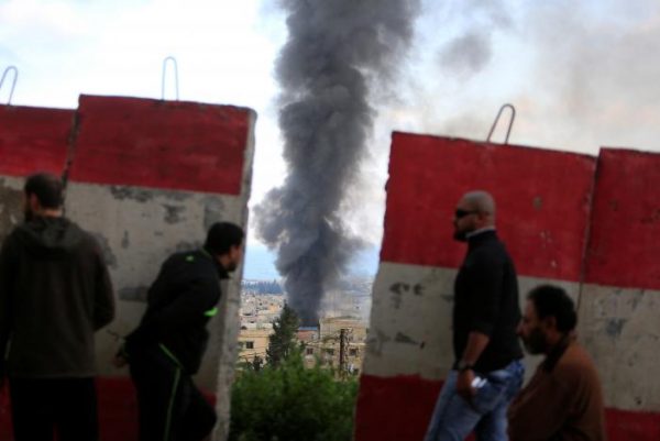 People stand behind a Lebanese Army barrier as smoke rises during clashes between Islamists and Palestinian Fatah gunmen in Ain al-Hilweh camp Palestinian refugee camp near Sidon, South Lebanon April 9, 2017. REUTERS/Ali Hashisho