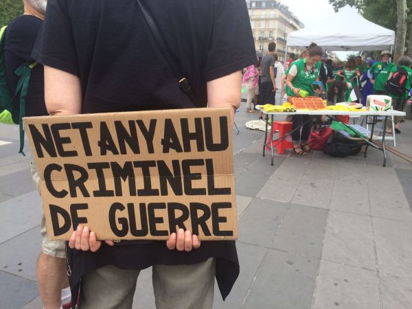 A demonstrator holds a sign that says "Netanyahu is a war criminal" at a protest in Paris, July 15 2017. 