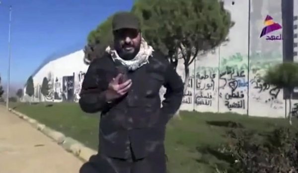 This frame grab from video provided on Friday, Dec. 8, 2017, by Asaid Ahl al-Haq's TV station al-Ahd, shows Iraqi militant commander Qais al-Khazali of the Iranian-backed Asaib Ahl al-Haq, or League of the Righteous, speaks in front of a wall that was built by Israel at the Fatima Gate border point in the southern village of Kfar Kila, Lebanon. A powerful Iran-backed Iraqi militant commander has visited the Lebanon-Israel border expressing support for the Lebanese and Palestinians against the Jewish state. (Al-Ahd TV station via AP)