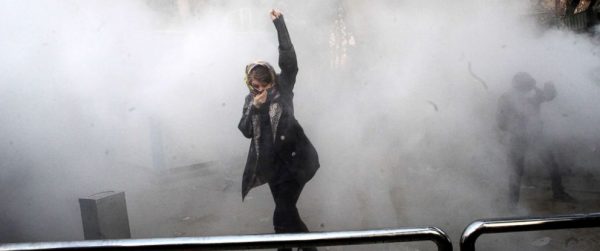 An Iranian woman raises her fist amid the smoke of tear gas at the University of Tehran during a protest driven by anger over economic problems, in the capital Tehran, Dec. 30, 2017.