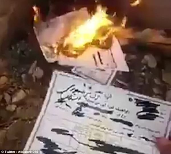 A government document is torched by an Iranian as anti-government unrest continues in the country