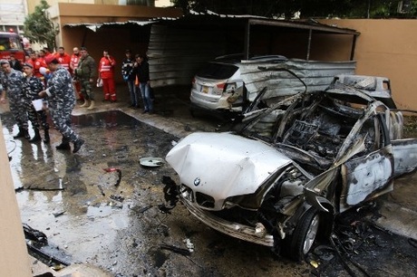 Lebanese security forces and emergency services stand near a damaged car following a car bomb blast in the southern Lebanese port city of Sidon on January 14, 2018.  / AFP PHOTO / Mahmoud ZAYYAT