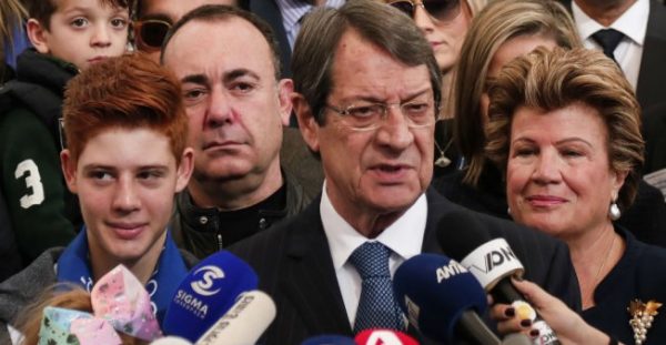 Amir MAKAR / AFP | Cypriot President Nicos Anastasiades (C) stands next to his wife Andri (R) as he addresses the media after casting his vote in the 2018 Cypriot presidential election at a polling station in the city of Limassol on January 28, 2018.