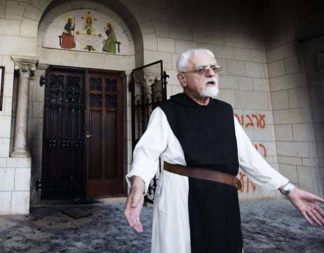 A Catholic monk stands in a doorway of the Latrun Trappist Monastery where Israeli police say Jewish vandals spray-painted anti-Christian and pro-settler graffiti and set the monastery’s door on fire, in Latrun, between Jerusalem and Tel Aviv, Israel. (AP/Oded Balilt)