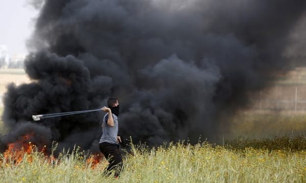 A Palestinian slings stones towards Israeli soldiers during clashes along the border with Israel. Photograph: Adel Hana/AP