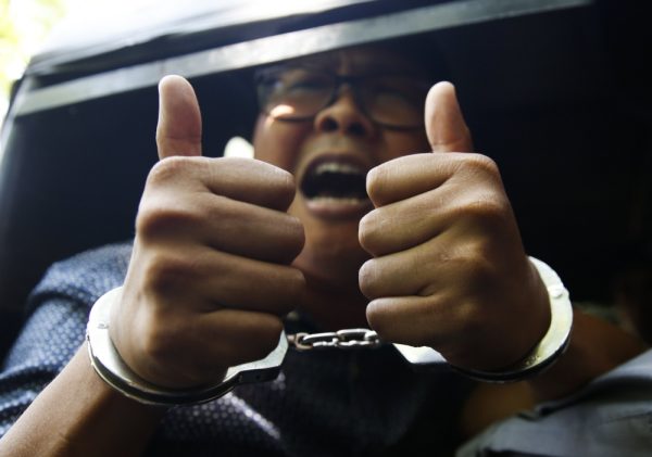 Detained Reuters journalist Wa Lone gestures to the media as he is escorted by police after a court hearing in Yangon, Myanmar April 11, 2018. REUTERS/Ann Wang 