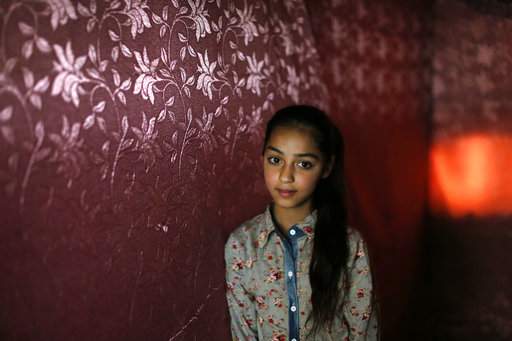 In this Tuesday, May 22, 2018 photo, Sarah, a Palestinian refugee from Syria, poses for a photo inside her family tent, in the eastern Bekaa Valley town of Kab Elias, Lebanon. Sarah has come a long way since she arrived in Lebanon after fleeing Syria’s civil war five years ago, and is now a star student at an elementary school run by the U.N. agency for Palestinian refugees, which also provides trauma counseling. But those services, and the thousands of children who rely on them, now face an uncertain future, as the U.S. threatens to cut funding. (AP Photo/Hassan Ammar), The Associated Press