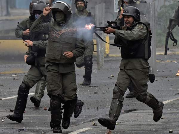 A member of the national guard fires hit shotgun at opposition demonstrators during clashes in Caracas last year (CARLOS BECERRA/AFP/Getty Images) 