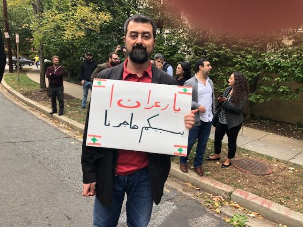  aprotester holding a placard that reads : "You crooks , because of you we had to emigrate "