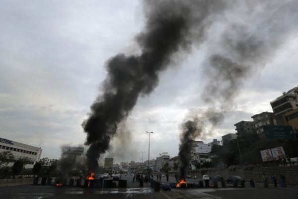 Anti-government protesters set fire to tires blocking a highway that links the capital Beirut to northern Lebanon during a protest against the Lebanese government in Zouk Mosbeh, north of Beirut, Lebanon, Monday, Oct. 28, 2019. (AP Photo/Hassan Ammar)