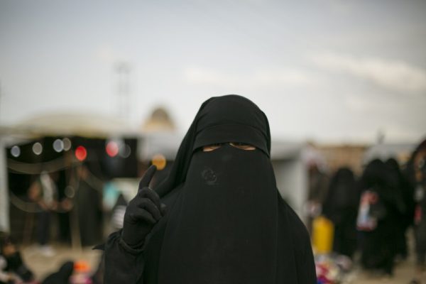 FILE  photo- In this March 31, 2019, file, photo, a woman gestures for a portrait at al-Hol camp, which holds families of Islamic State members, in Hasakeh province, Syria. Security conditions in the al-Hol camp that is home to tens of thousands of wives and children of Islamic State group fighters has been bad for the past months and will likely get worse now that Turkey is on the offensive in northern Syria. The camp that is home to more than 70,000 has witnessed crimes carried out by IS women against residents whom they consider apostates.(AP Photo/Maya Alleruzzo, File)