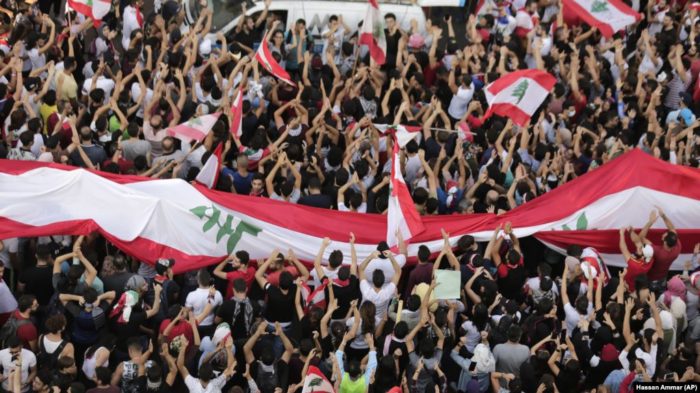 Demonstrators carry the national flag and banners during an anti-government protest in downtown Beirut, Lebanon October 21, 2019. REUTERS/Ali Hashisho