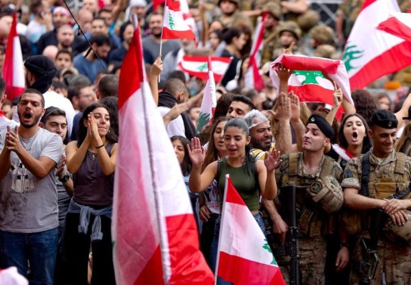 Anti-government protesters wave national flags as Lebanese army soldiers form a human barrier in the area of Jal el-Dib in the northern outskirts of the Lebanese capital of Beirut. Patrick