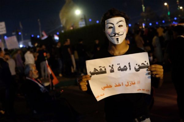 An Iraqi protester holds a placard reading "We are an invincible nation" during ongoing anti-government demonstrations in the Shiite shrine city of Karbala, south of Iraq's capital Baghdad, on November 1, 2019. - Iraq's top cleric warned foreign actors against interfering in his country's anti-government protests as they entered their second month despite pledges of reform and violence that has left over 250 dead. The demonstrations have evolved since October 1 from rage over corruption and unemployment to demands for a total government overhaul -- shunning both politicians and religious figures along the way. (Photo by Mohammed SAWAF / AFP) (Photo by MOHAMMED SAWAF/AFP via Getty Images)