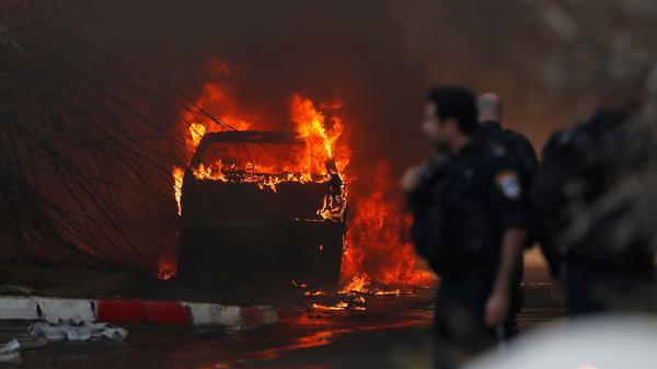 A vehicle burns outside a factory that was apparently hit with rocket fire Tuesday in the southern Israeli town of Sderot. Israel's military announced it had killed a commander of the Palestinian militant group Islamic Jihad in an early morning strike on his home in the Gaza Strip, prompting retaliatory barrages from Gaza.